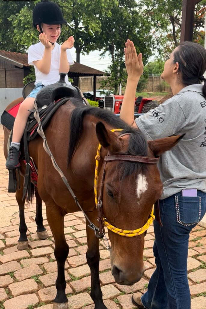 Menina montada a cavalo com apoio assistencial