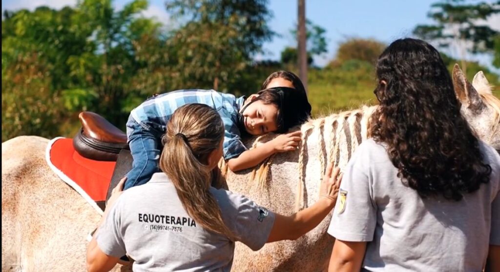 Assistente do Centro apoiando um jovem montado no cavalo