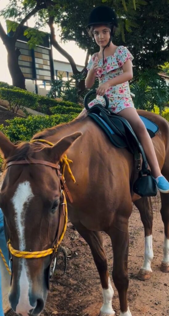 Menina com roupa florida montada em um cavalo