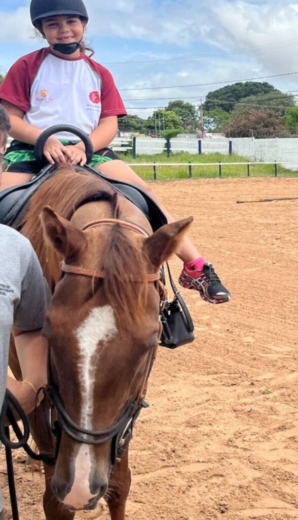 Menina sorrindo montada no cavalo